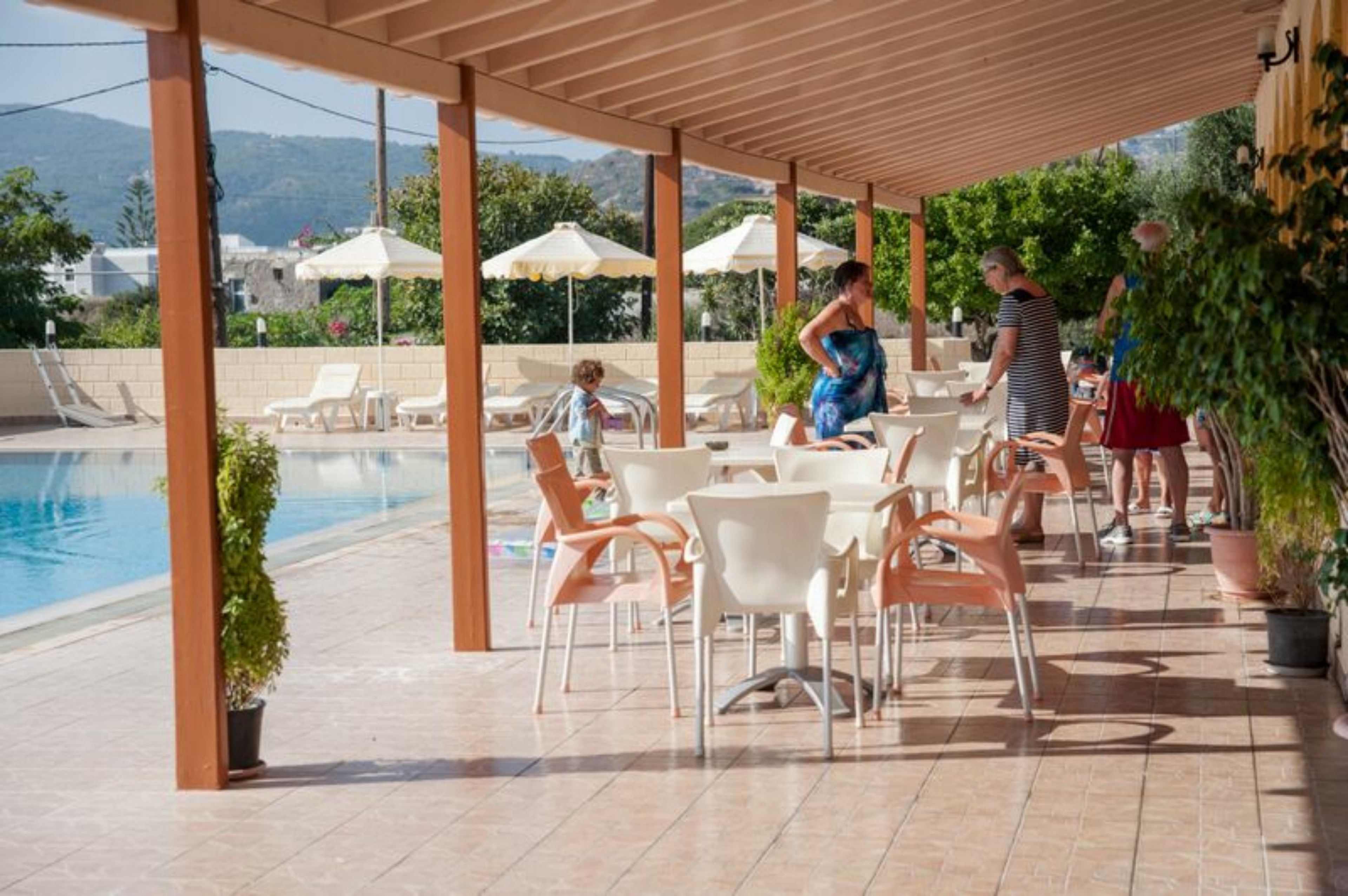 A covered outdoor area with a pool, lounge chairs, and tables.