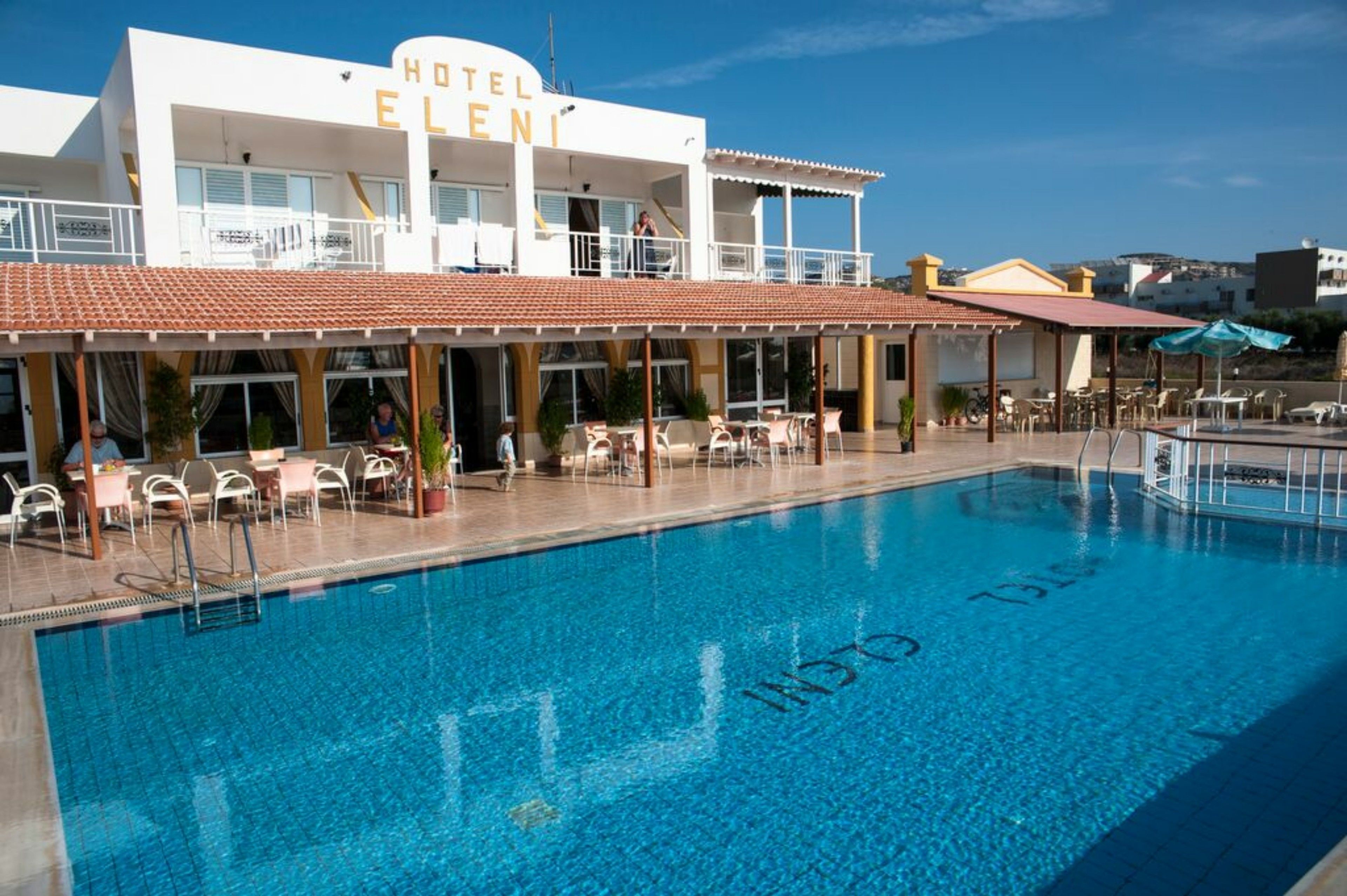 Un hotel con piscina, mobiliario exterior y zona cubierta.