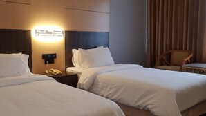 A hotel room with two beds, a bedside table with a phone, and a wall-mounted light fixture. - Ariston Hotel (Bangkok)