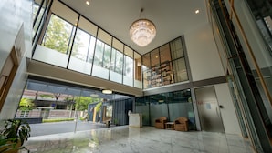 A spacious lobby with a marble floor, large windows, and a chandelier. - Ariston Hotel (Bangkok)