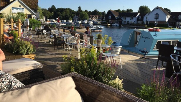 A waterfront restaurant with outdoor seating overlooking a marina. - Hotel Wroxham (Norwich)