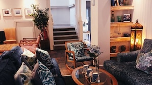 A cozy living room with a sofa, armchair, and coffee table. A staircase leads to an upper level. - Hotel Wroxham (Norwich)