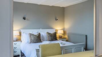A bedroom with a bed, two bedside lamps, a nightstand, and a chair.
