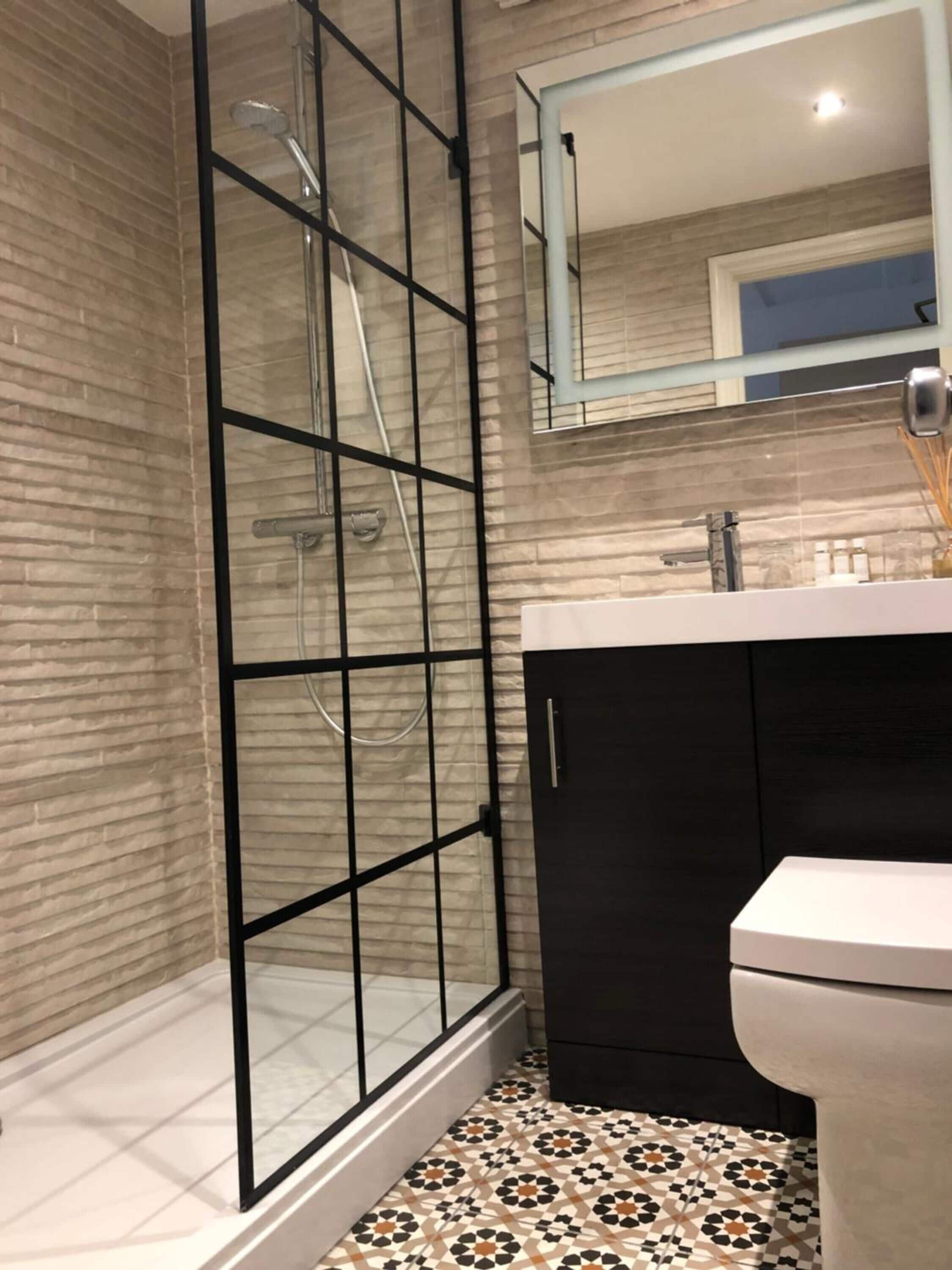 Een moderne badkamer met een douchecabine van glas, een zwart kastje en een wit toilet.
