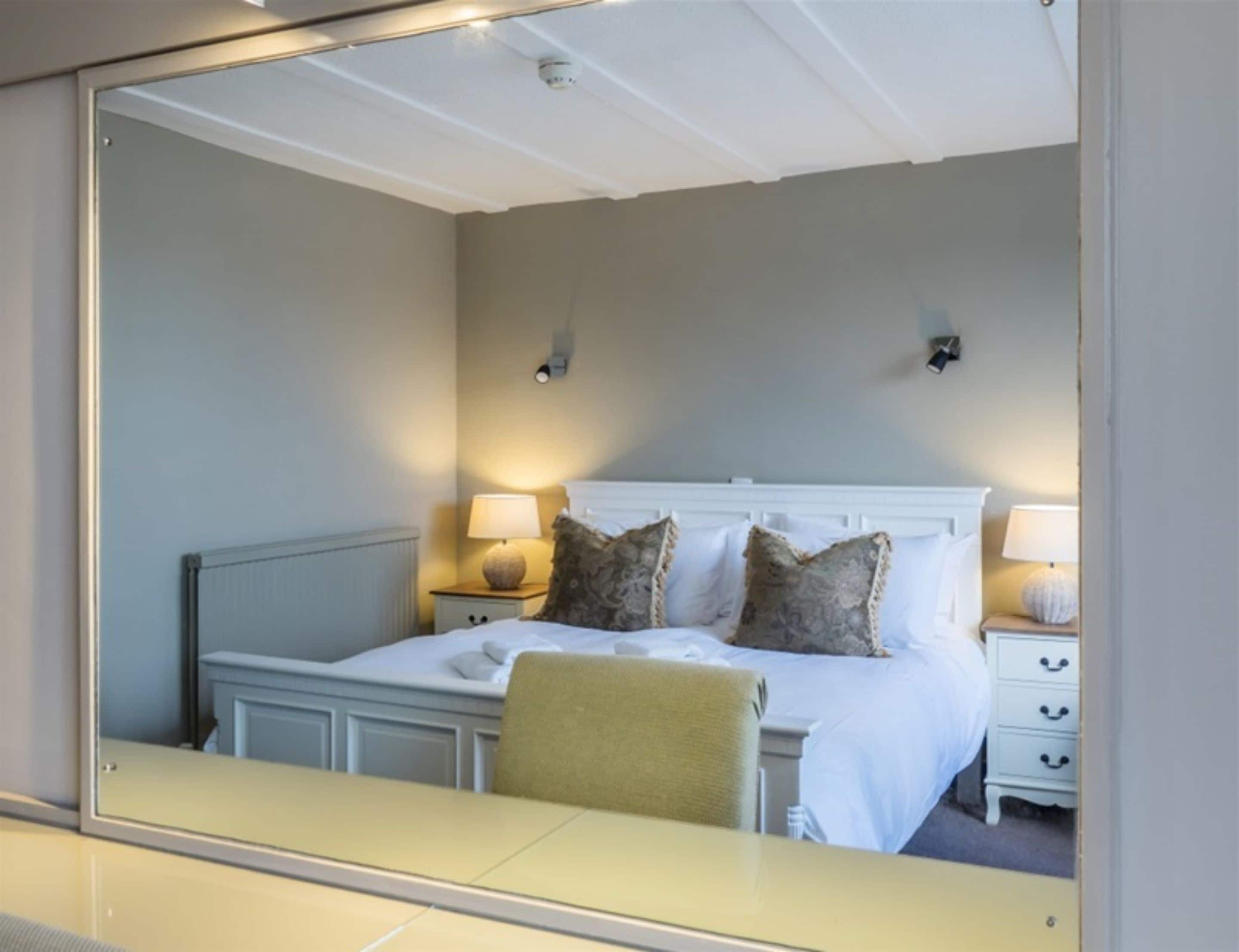 Une chambre à coucher avec un lit, des tables de chevet, des lampes et une chaise.