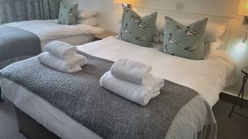 A hotel room with two beds, each with white linens and matching pillows. There are towels neatly folded on the beds.