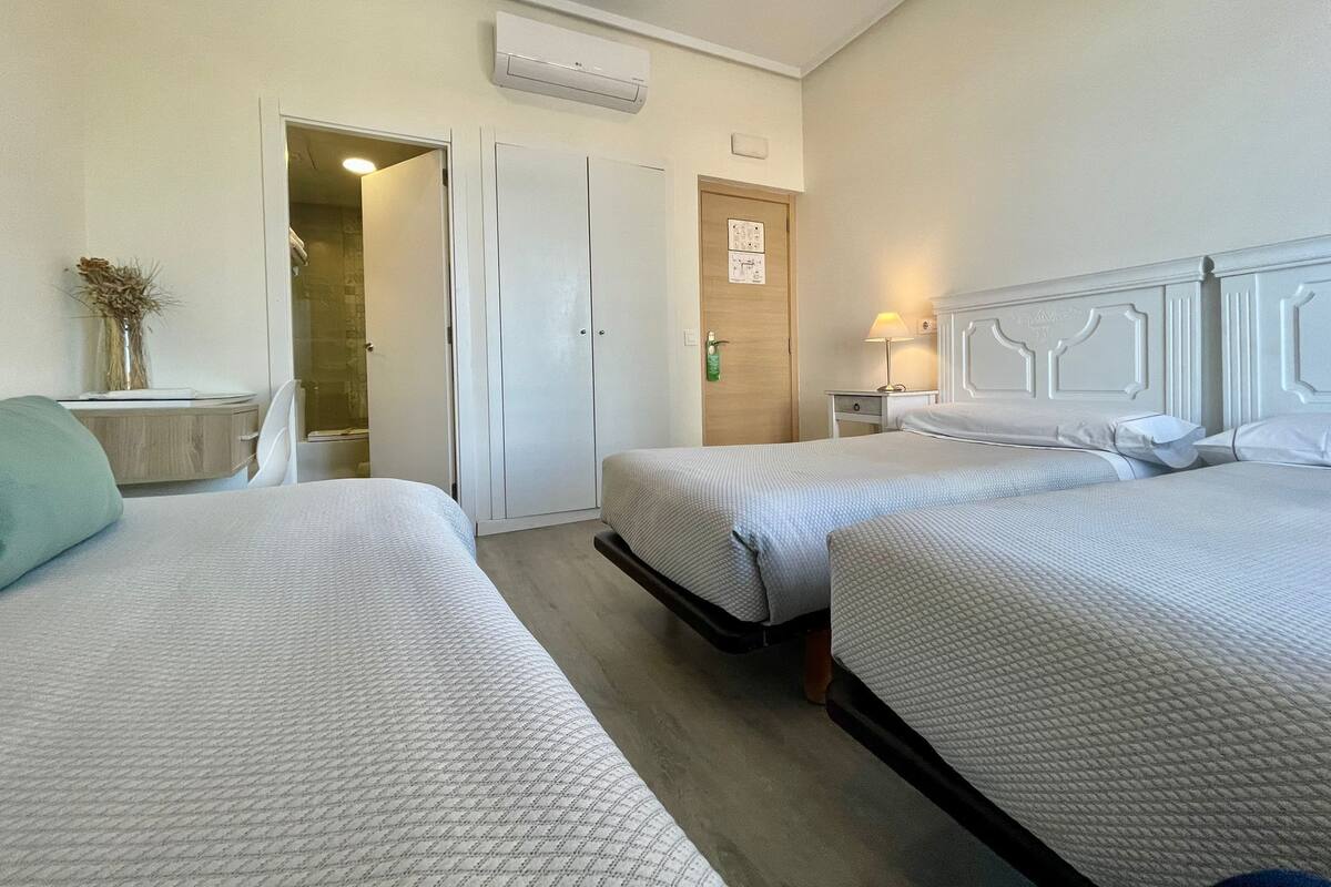 Habitación de hotel con dos camas, un baño y un escritorio pequeño.