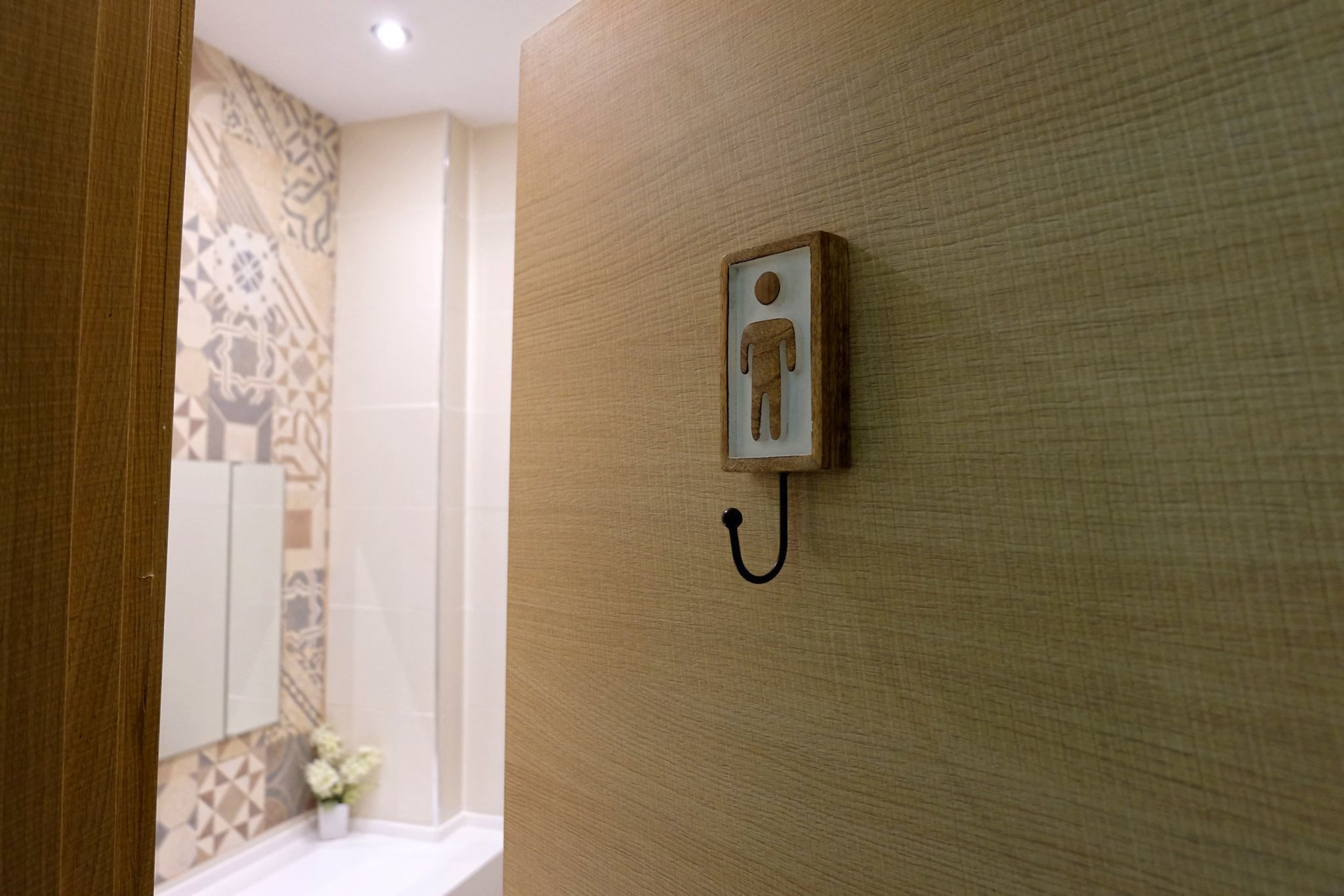 A bathroom with a wooden wall, a tiled shower area, and a toilet sign.