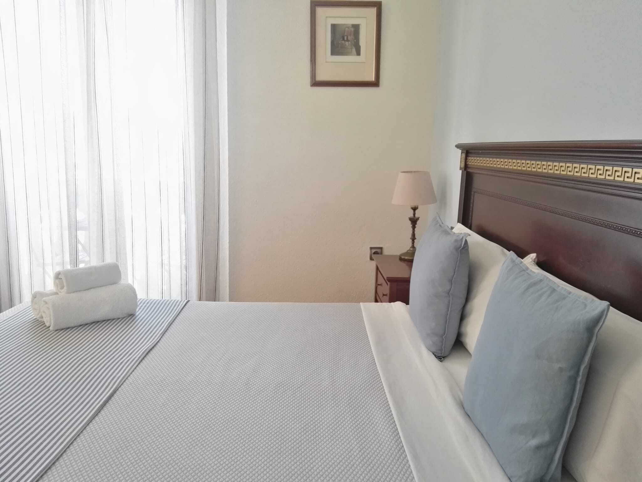 Uma cama bem arrumada com um edredom listrado, um travesseiro e uma toalha enrolada ao lado.