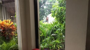 A corner with two red chairs, a small table, and a window with a view of greenery outside. - Kode Inn (Tagbilaran)