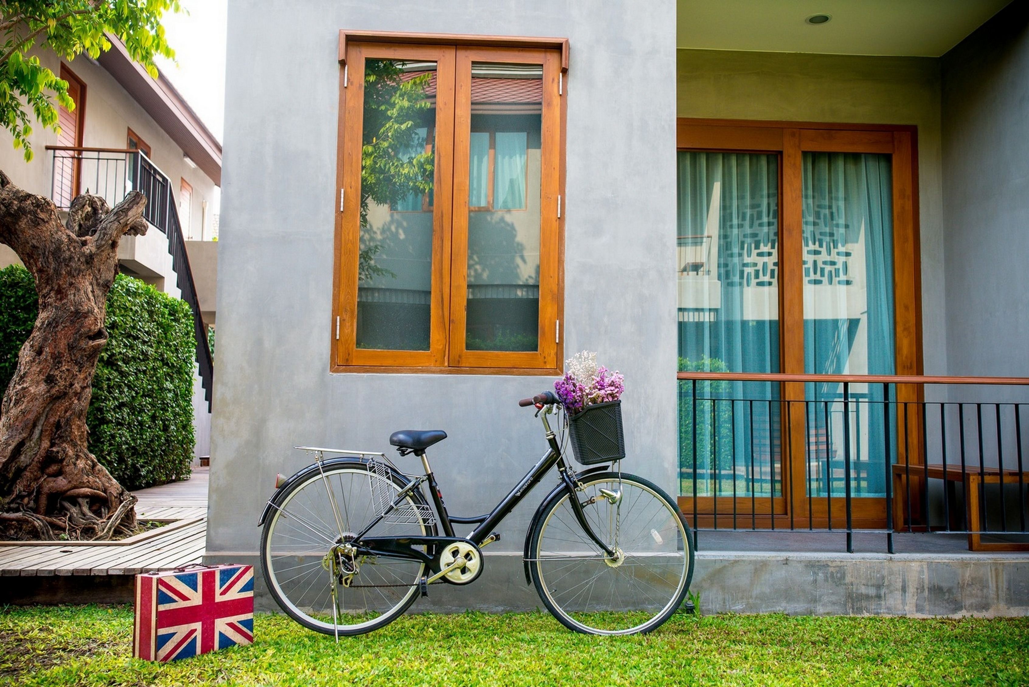 Una bicicleta estacionada frente a un edificio con un ventanal grande y un balcón.