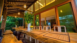 Un comedor amplio con una larga mesa de madera y sillas, rodeado de grandes ventanales con vistas al exterior.
