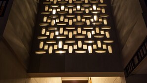 Una escalera moderna con escalones de madera y un lámpara de diseño geométrico.