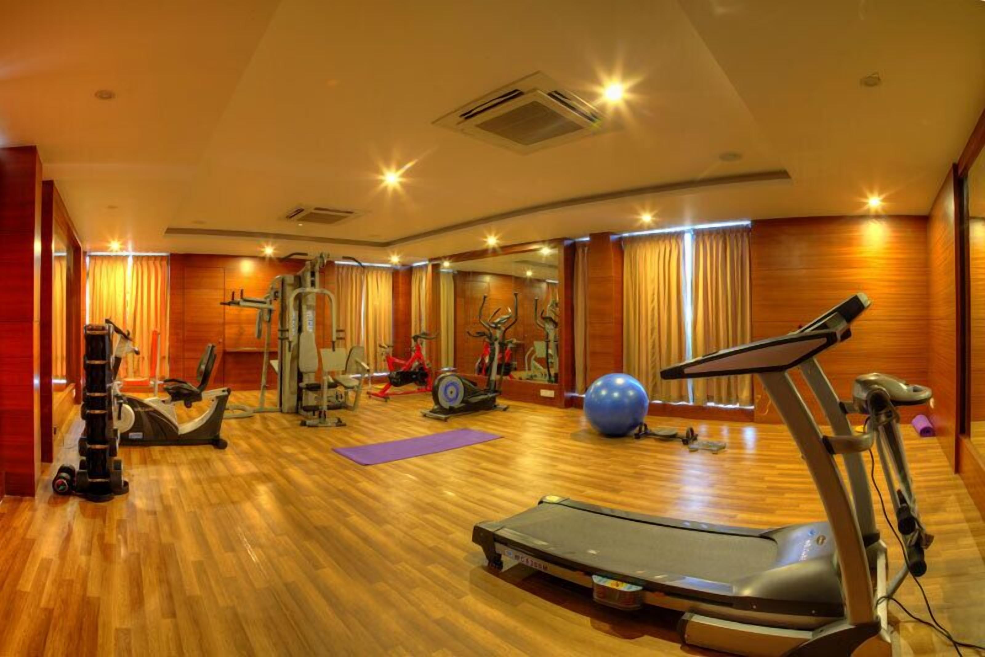 A gym with exercise equipment, a treadmill, and a large exercise ball.