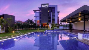 A modern hotel with a swimming pool, surrounded by greenery and a clear sky. - Hotel Le Ruchi the Prince (Mysore)