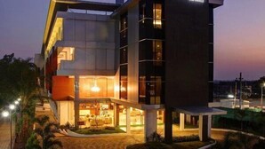 A modern hotel with a prominent sign, a covered entrance, and a landscaped area. - Hotel Le Ruchi the Prince (Mysore)