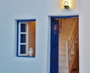 A white building with a blue door and a small window. - Fira white residence (Santorini)