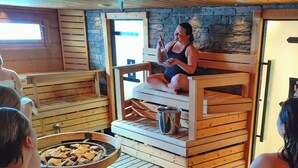 A sauna with wooden benches and a stone wall. - Arctic SnowHotel & Glass Igloos (Rovaniemi)