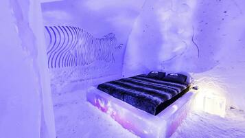 Una habitación de hotel de hielo con cama y una escultura de hielo única.