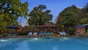 Un área de piscina con sillones de descanso y un pabellón.