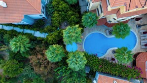 An aerial view of a residential area with a swimming pool surrounded by lush greenery and red-tiled roofs. - Dores Residence (Marmaris)