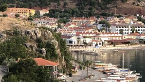 A coastal town with a marina, buildings with red-tiled roofs, and a rocky hillside. - Dores Residence (Marmaris)