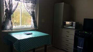 A small kitchen with a table, a refrigerator, and a microwave.