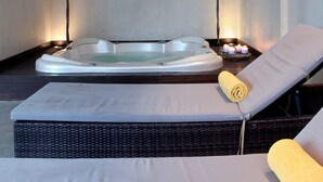 A spa room with a hot tub, two candles, and a lounge chair with a towel. - Egnatia City Hotel & Spa (Kavala)