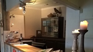 A rustic bar area with a wooden counter, newspapers, and a candle. - Bykle Hotell  (Bykle)