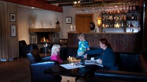 A cozy lobby with leather seating, a fireplace, and a bar area with various bottles. - Bykle Hotell  (Bykle)