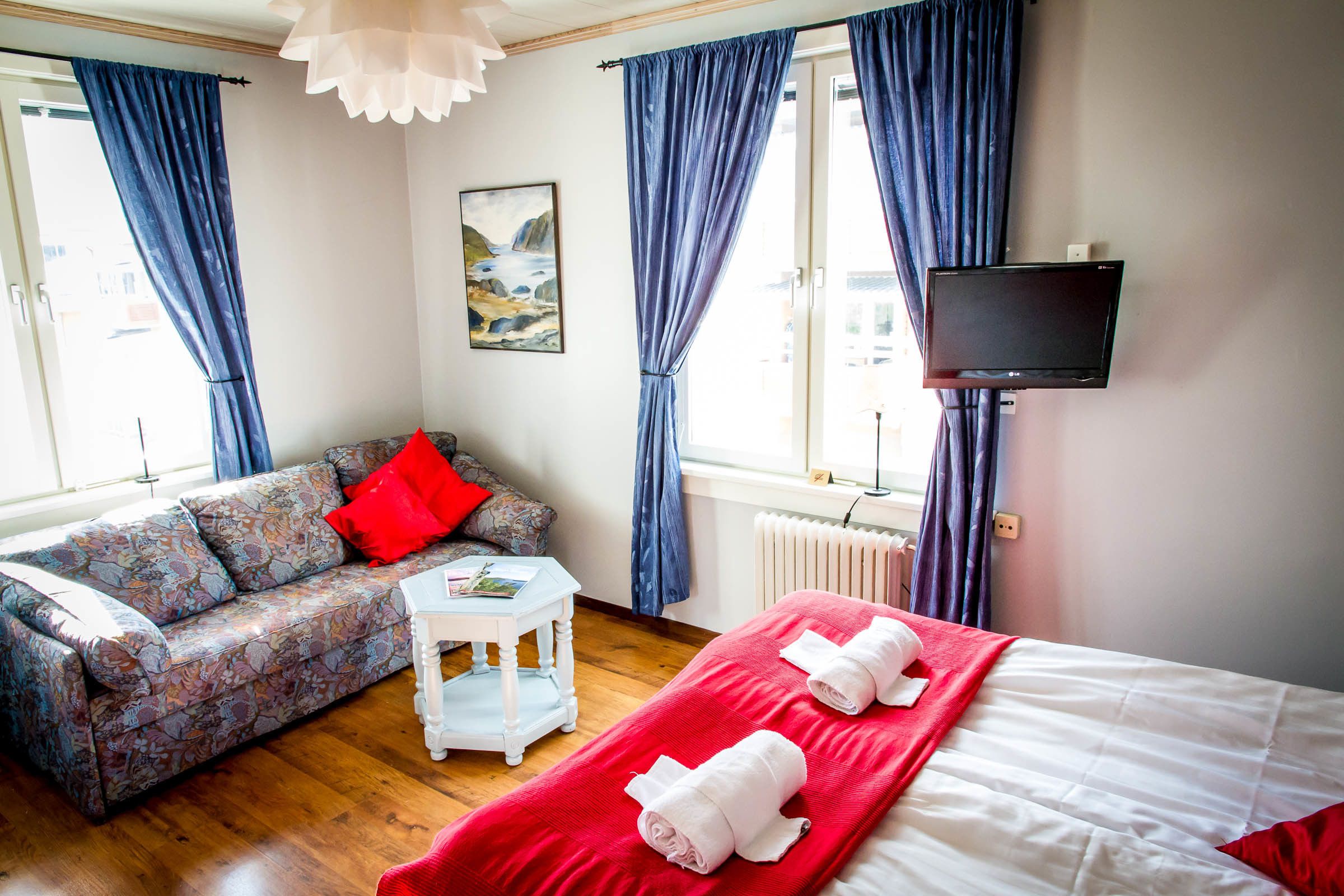 Une chambre d’hôtel avec un canapé, un lit, une télévision et un tableau au mur.