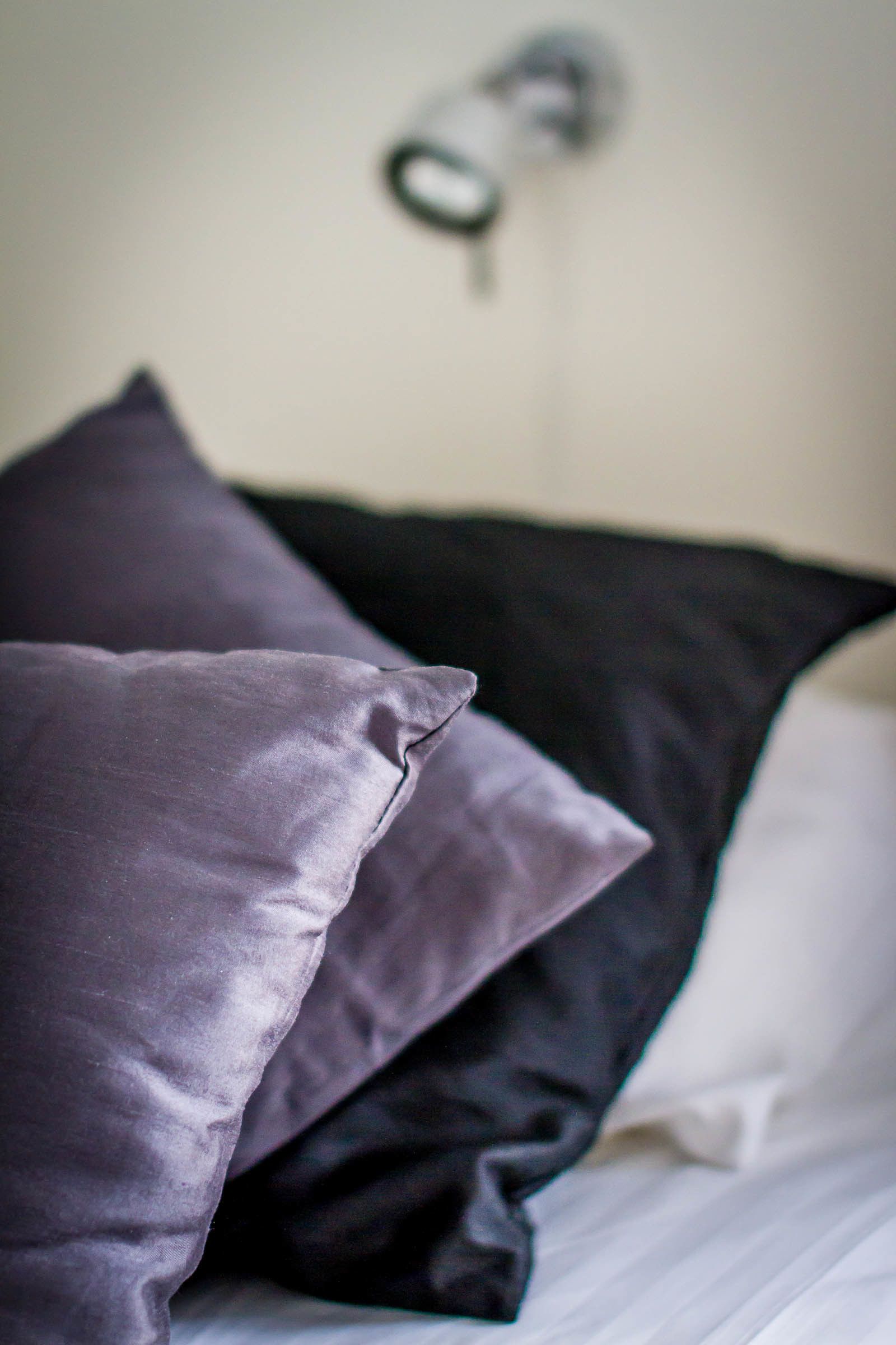 Un lit avec des oreillers dans des tons de violet et de noir.