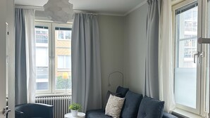 Una sala de estar moderna con un sofá gris, una pequeña mesa redonda con una planta y una silla negra.