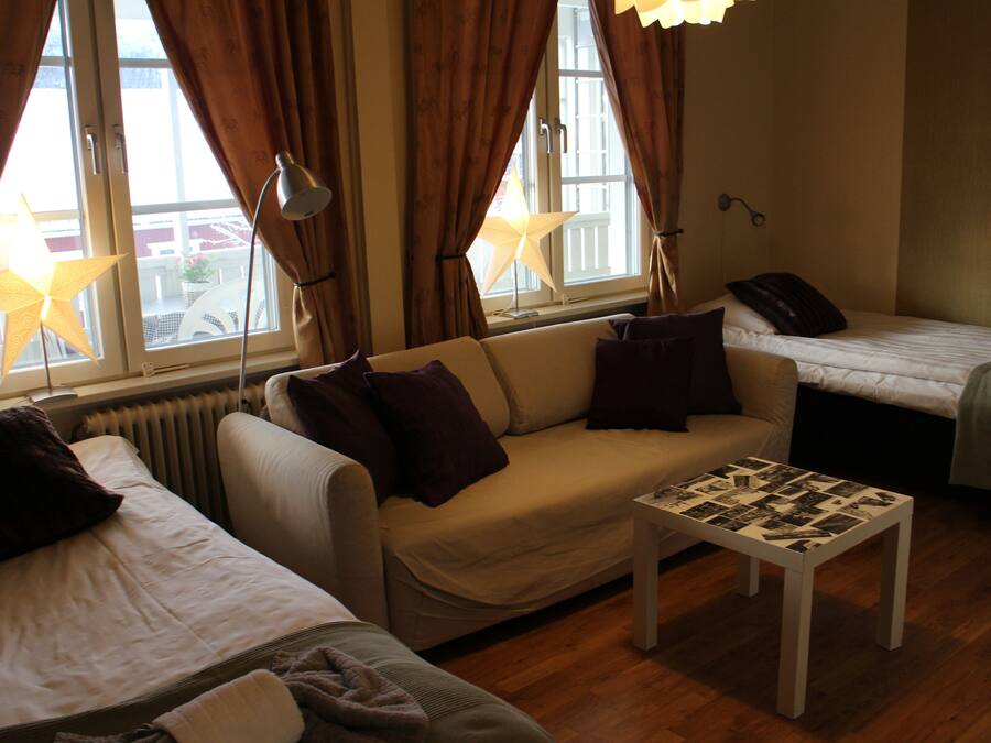 Una habitación de hotel acogedora con sofá, una mesita y una cama individual.
