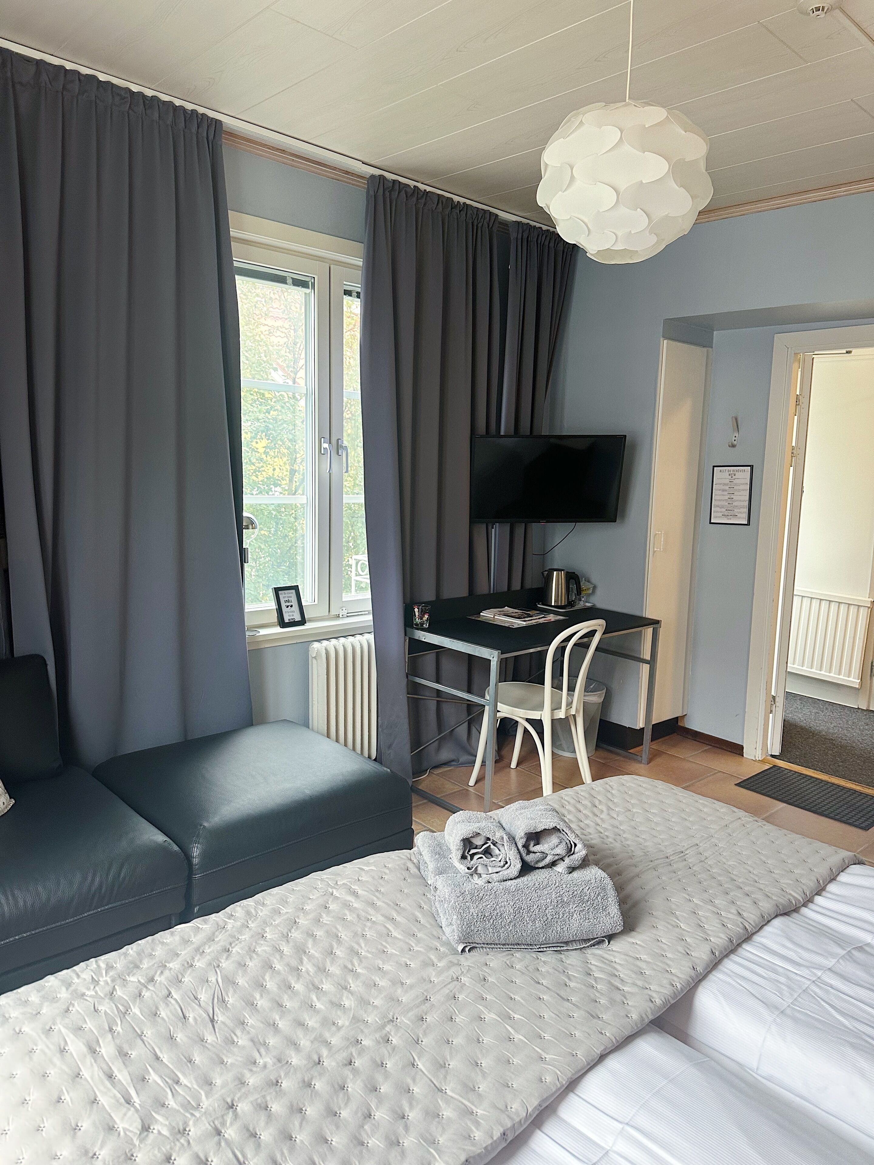 A hotel room with a bed, a desk, a chair, and a television.