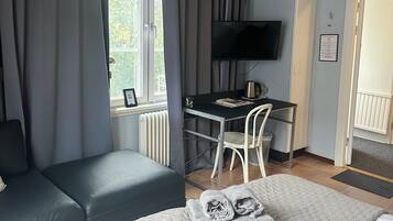 A hotel room with a bed, a desk, a chair, and a television.