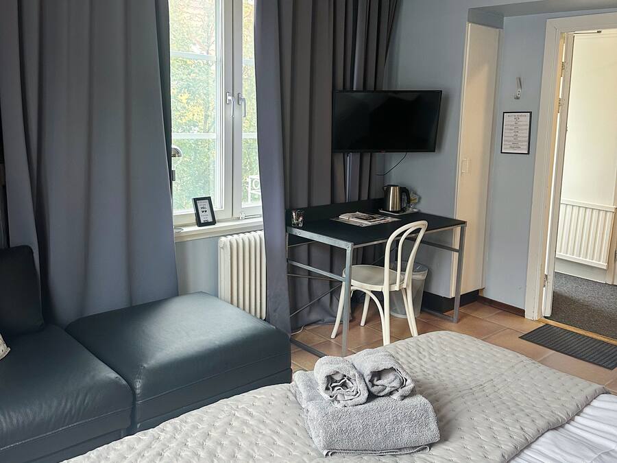 A hotel room with a bed, a desk, a chair, and a television.