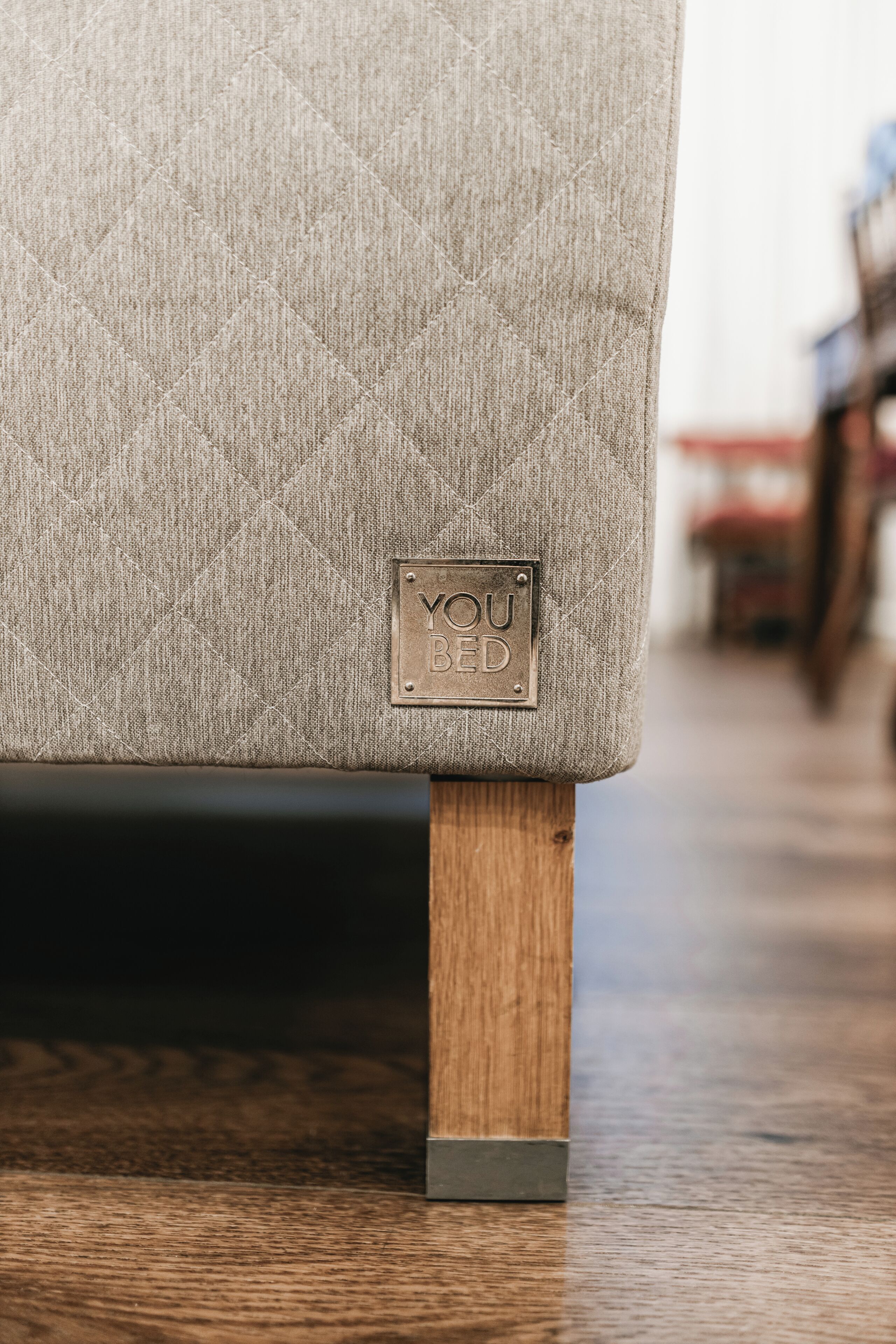 Een detailopname van een comfortabele fauteuil met een gewatteerd patroon en een metalen plaat waarop staat 