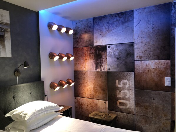 Un dormitorio moderno con una cama, una mesita de noche y una lámpara de pared.