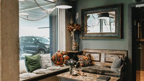 Ein gemütliches Wohnzimmer mit Holzbalkendecke, einem großen Fenster, einer Sofagarnitur, einem Couchtisch und einer Pendelleuchte.