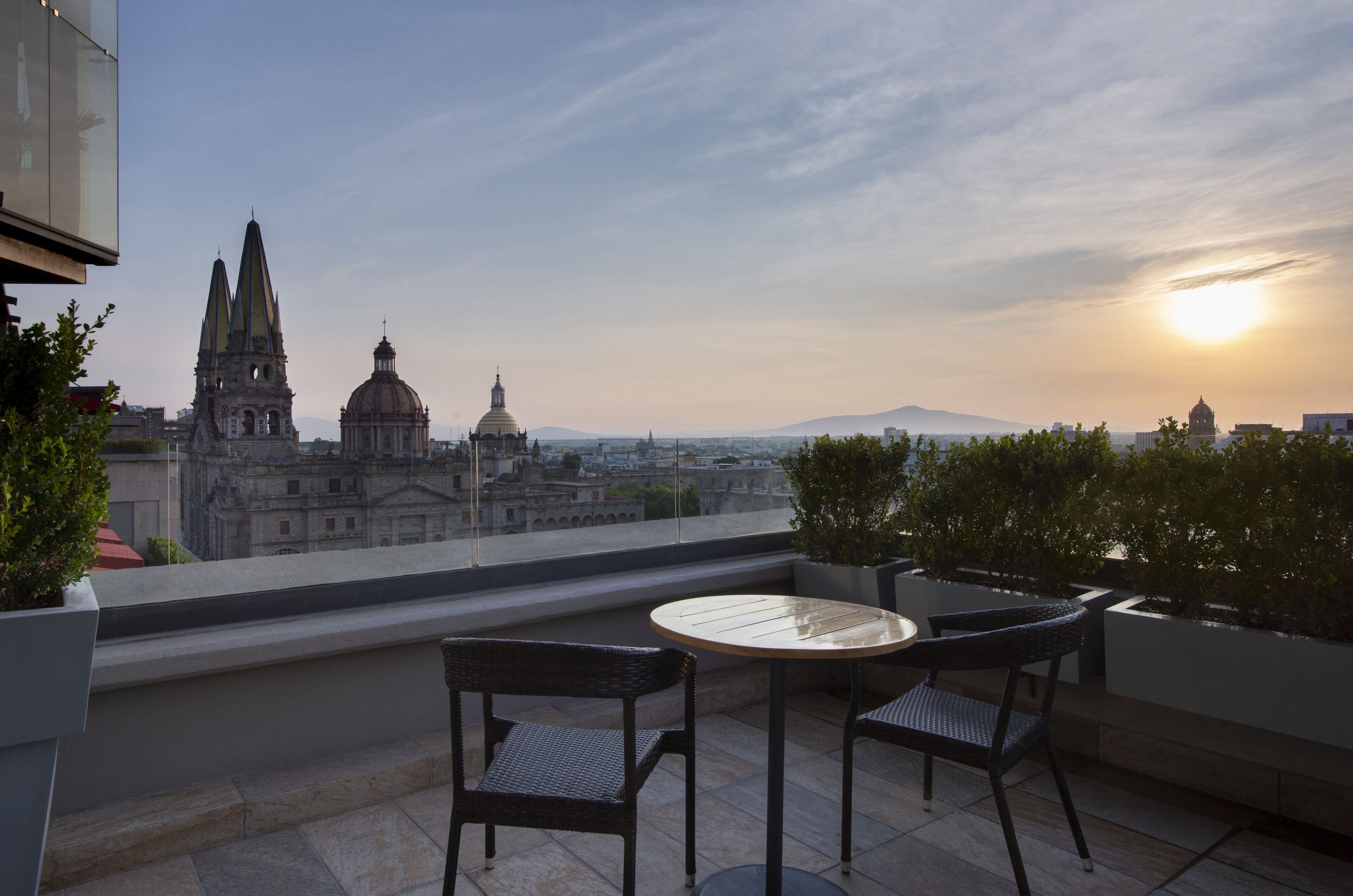 Una terrazza con tavolo e sedie che si affaccia su una città con edifici storici e una montagna sullo sfondo.