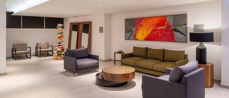 A modern living room with a sofa, two armchairs, a coffee table, and a bookshelf.