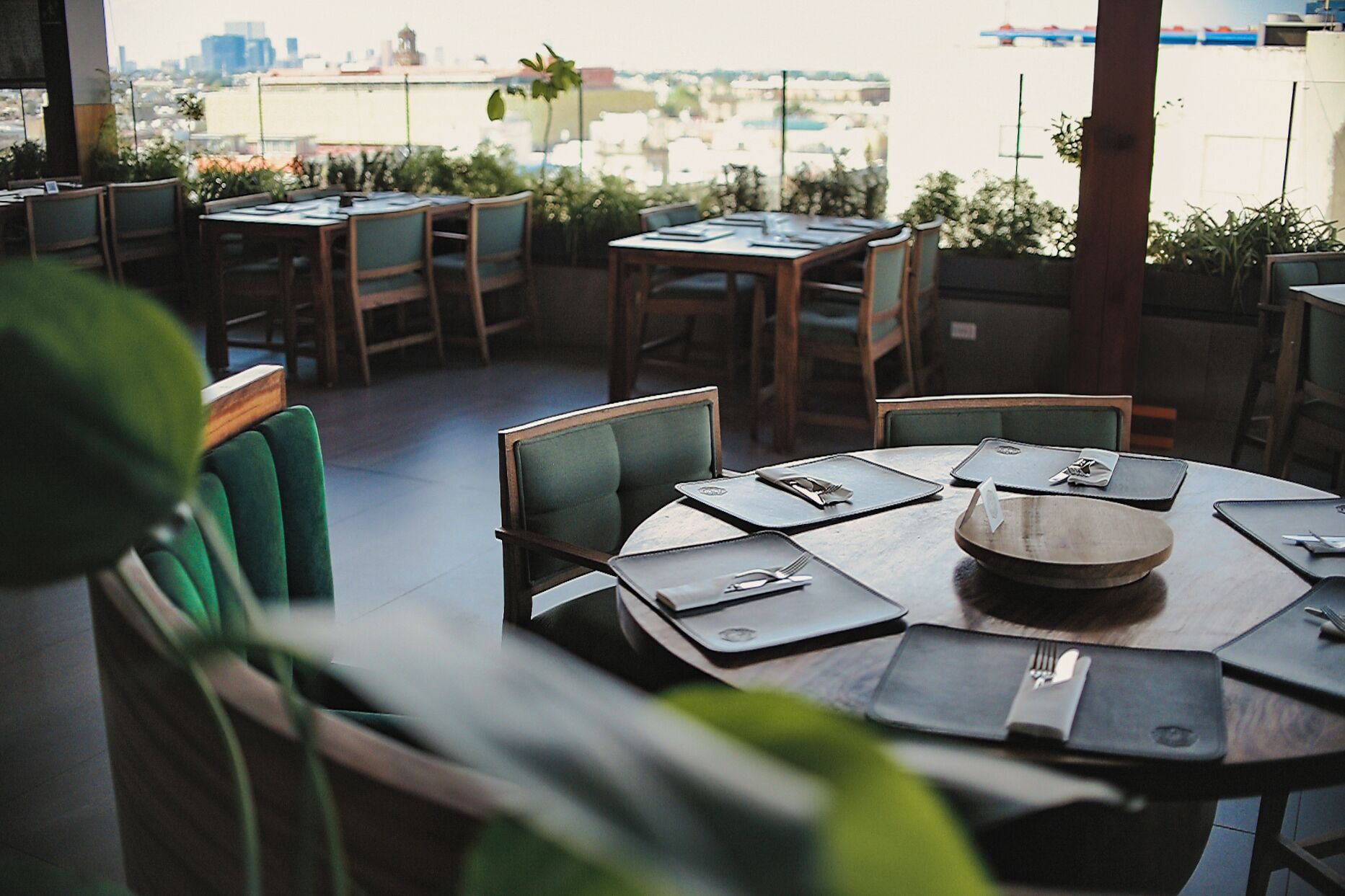 Ein Restaurant mit runden Tischen, Stühlen und Blick auf die Stadt.