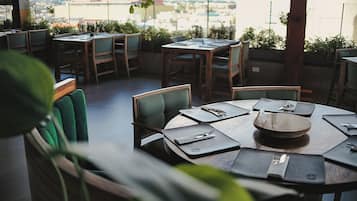 Ein Restaurant mit runden Tischen, Stühlen und Blick auf die Stadt.