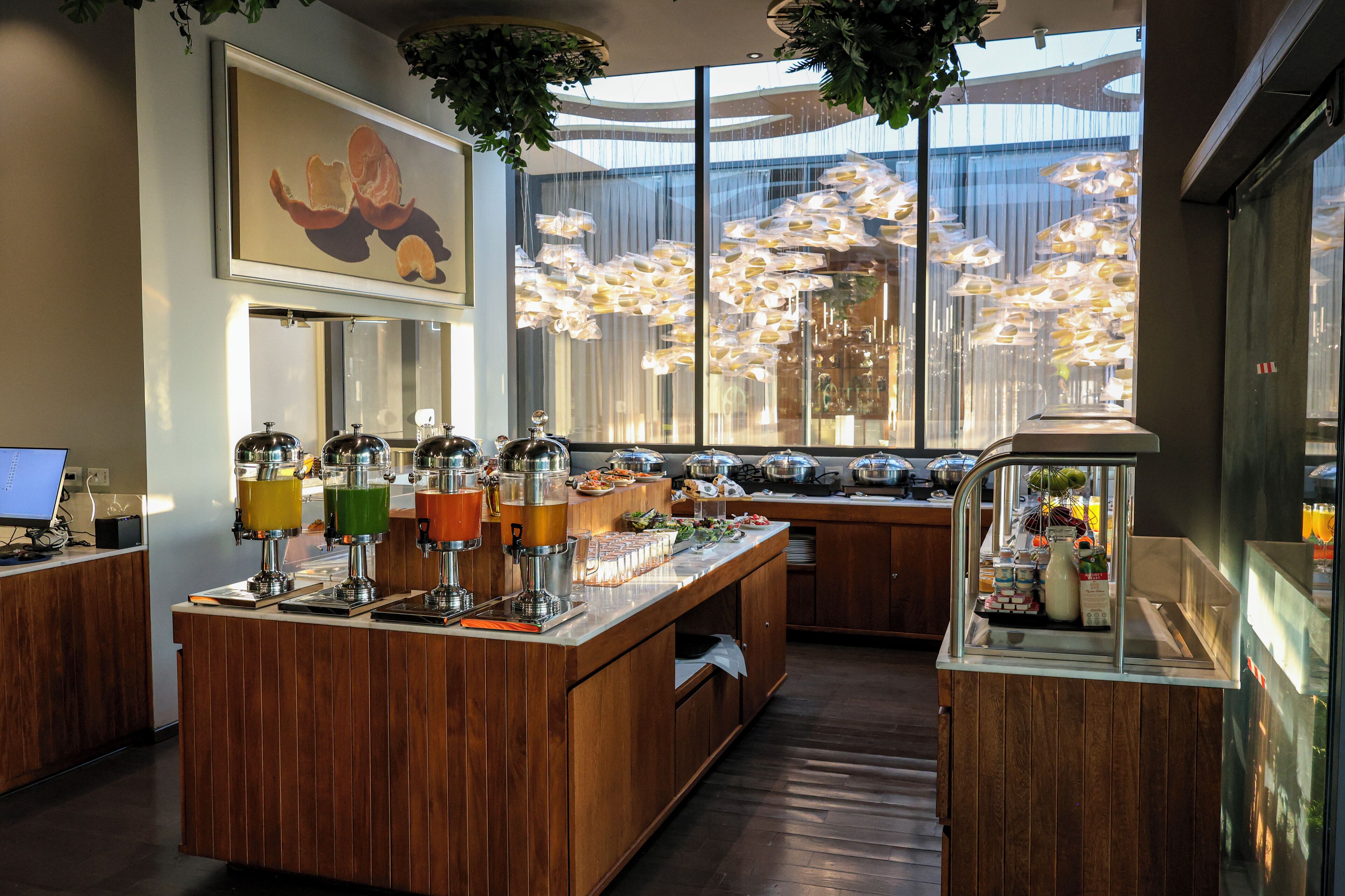 Zona de bar moderna con mostrador de madera, varios dispensadores de bebidas y vistas de la ciudad a través de amplias ventanas.