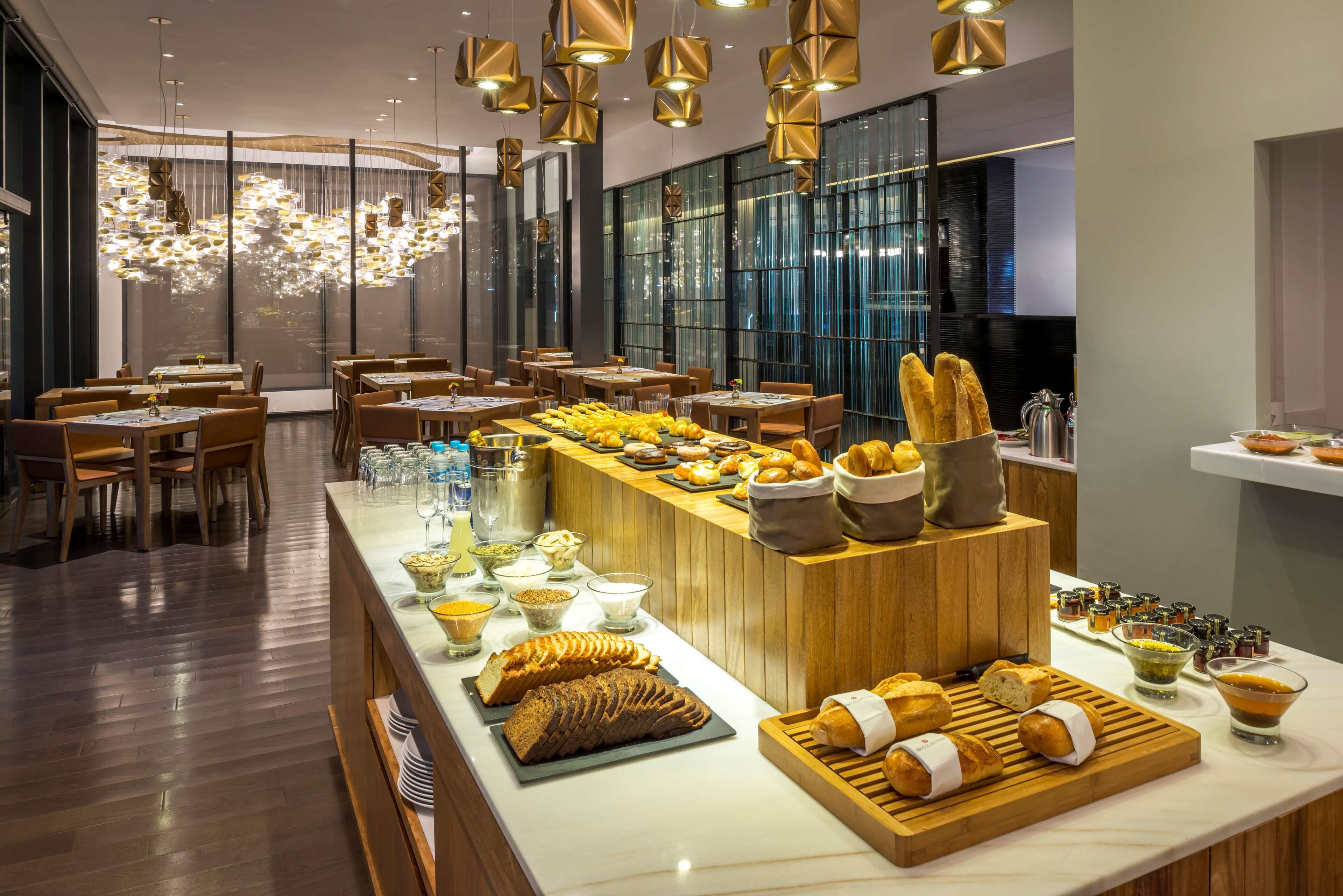 A modern restaurant with a wooden counter displaying various breads and pastries.