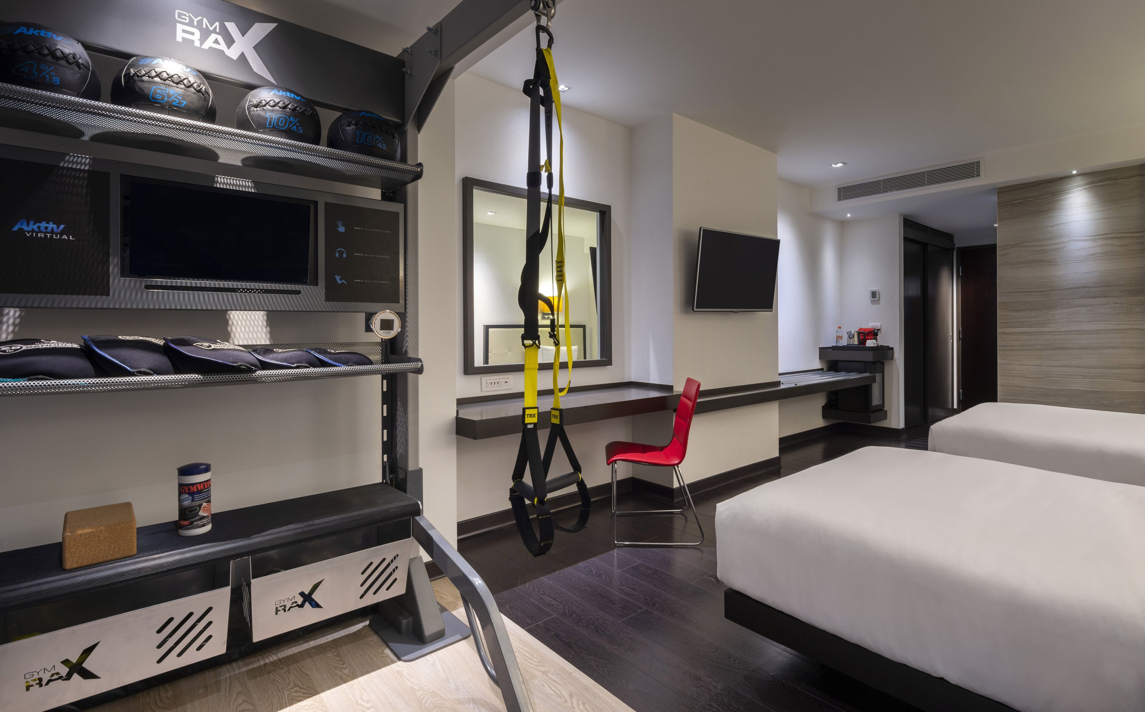 Une chambre d’hôtel équipée d’un lit, d’un bureau, d’une chaise, d’une télévision et de matériel d’exercice.