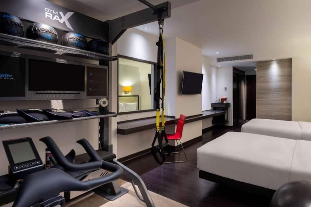 Ett hotellrum med en säng, träningsutrustning, en tv och ett skrivbord.