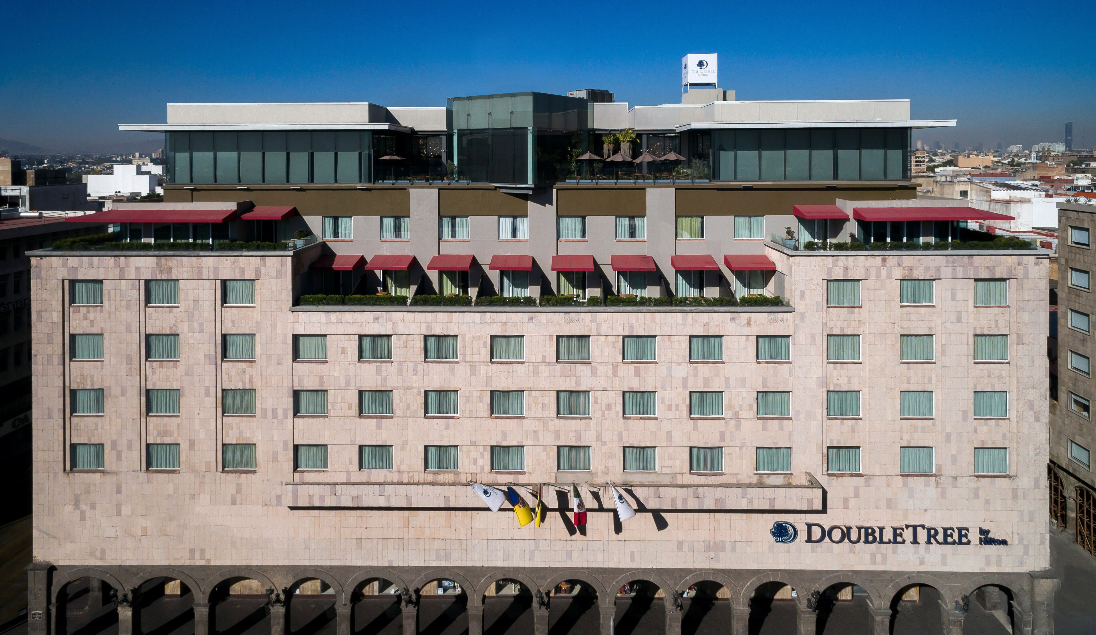 A hotel with a modern design, featuring a flat roof, multiple balconies, and a prominent DoubleTree logo.