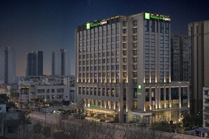 Et hotel med flere etager, med et tydeligt Holiday Inn Express skilt, omgivet af andre bygninger og en klar nattehimmel.